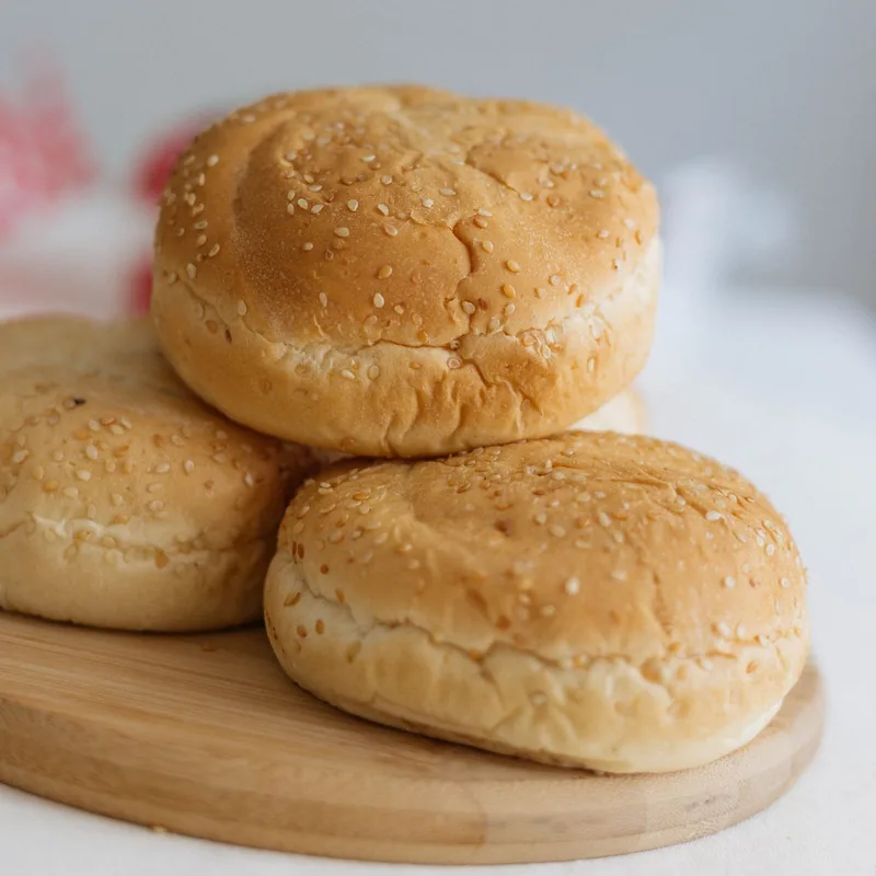 Freshly baked burger buns on a wooden board