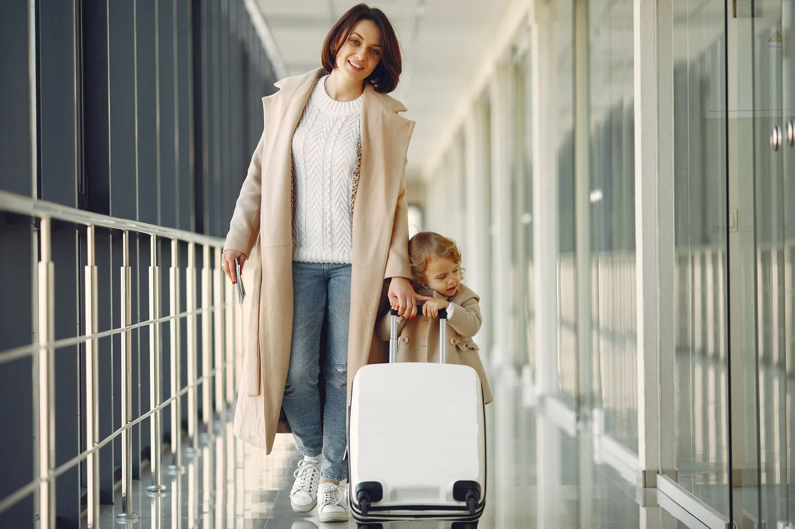 A mother and daughter with luggage, ready for a trip at the airport