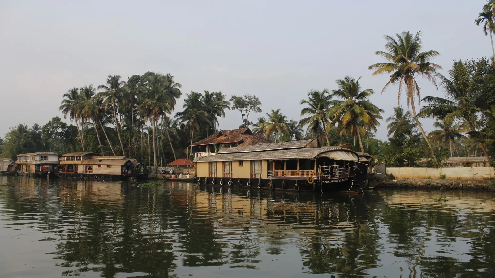 Kerala backwaters at sunrise with a traditional houseboat among palms