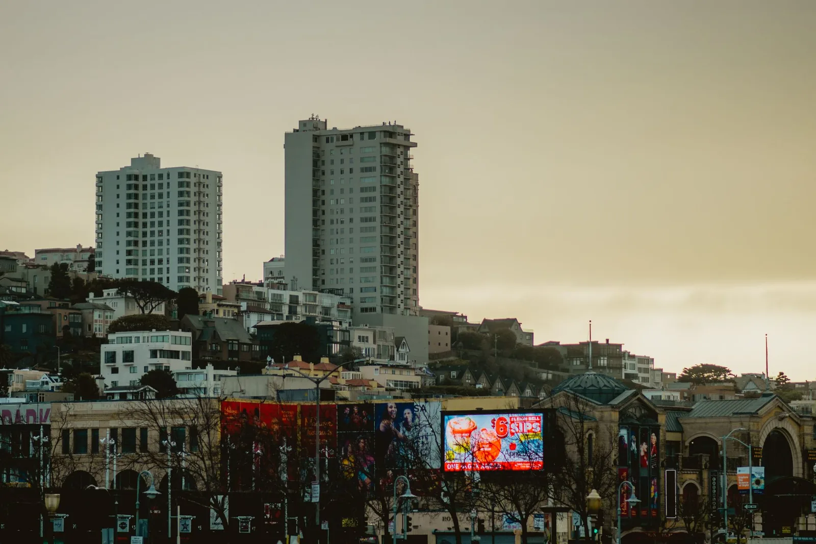 Large outdoor billboard hoardings against a city skyline at dusk