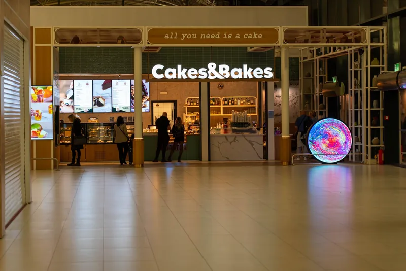 A glowing circular digital advertising screen beside a storefront in a shopping mall