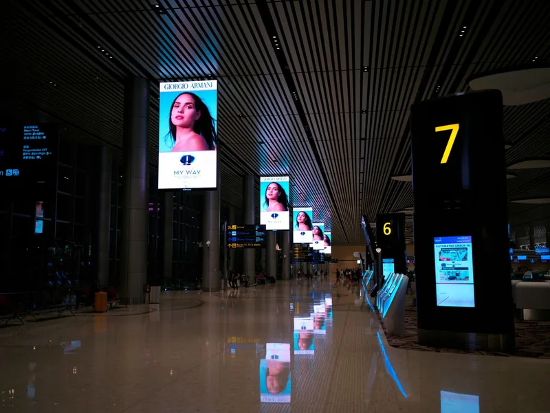 Digital advertising screens lining an airport concourse at night
