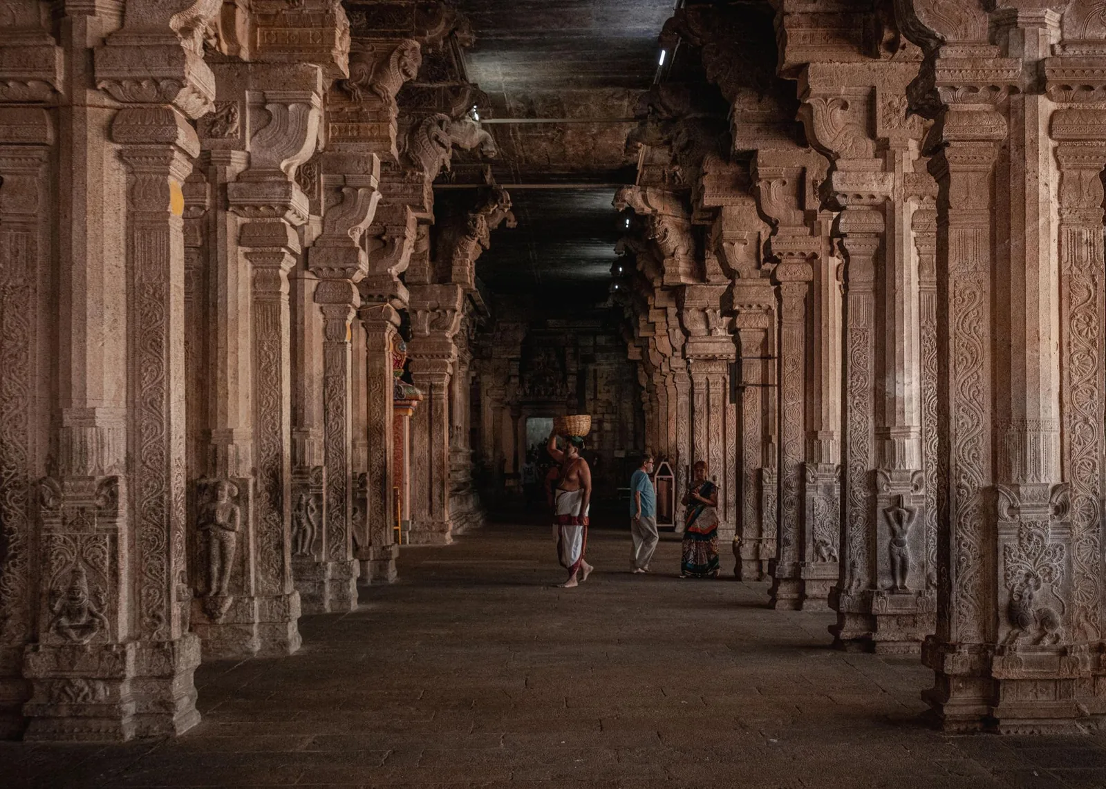A long temple corridor lined with carved stone pillars