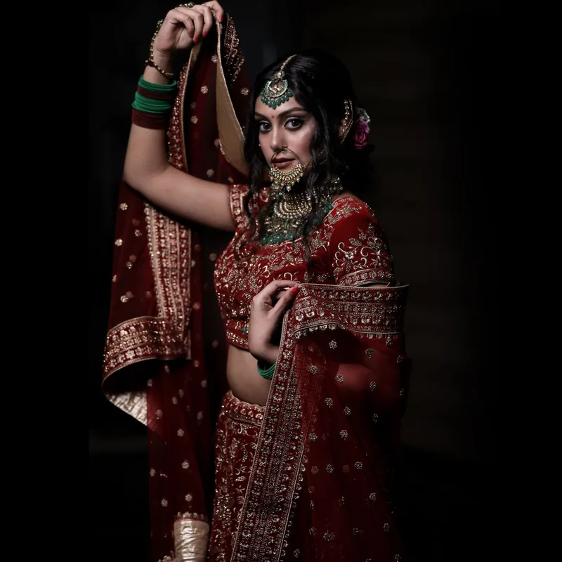 A bride in a richly embroidered deep red bridal lehenga