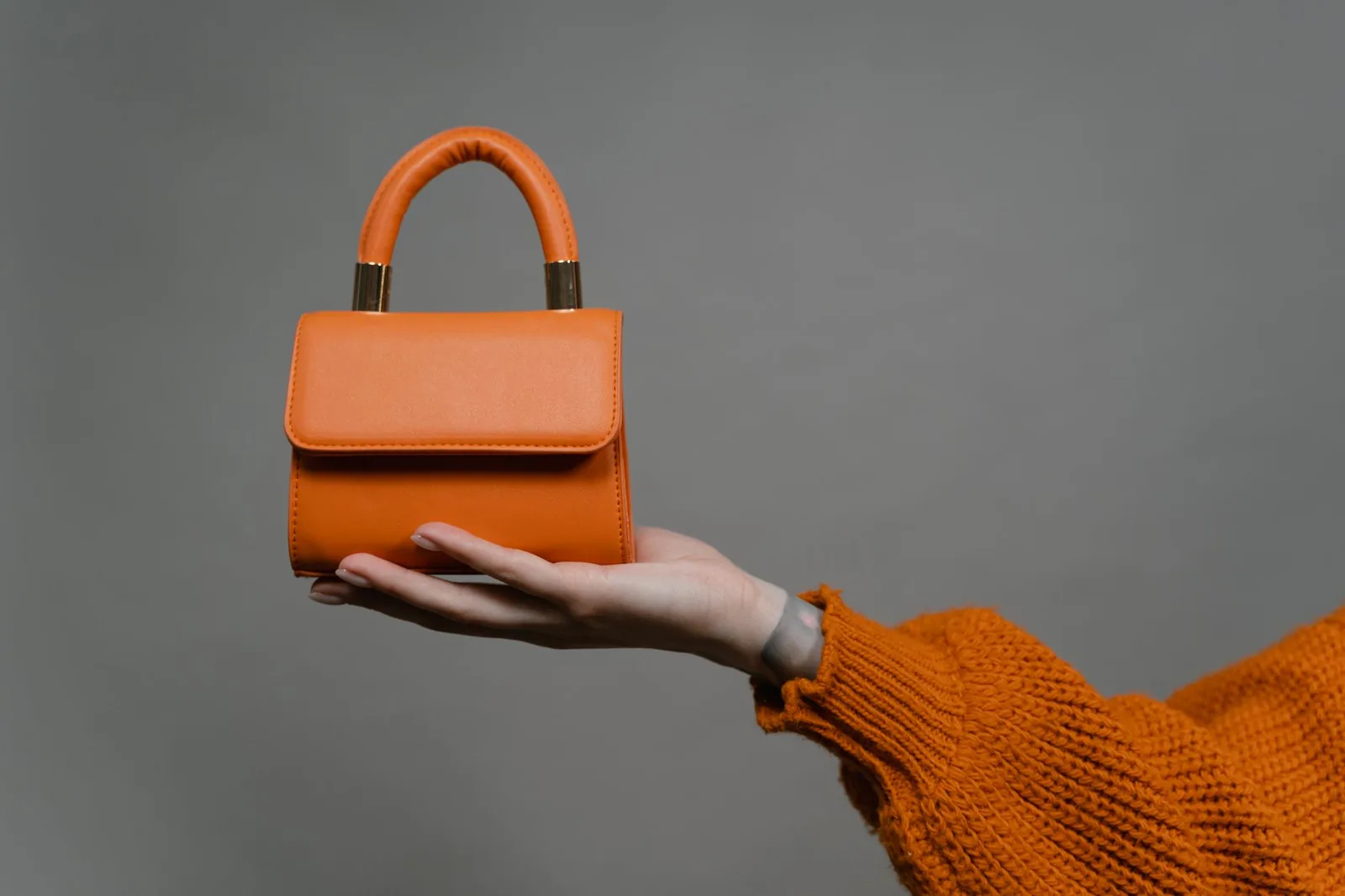 Woman carrying a minimal leather handbag in soft editorial light
