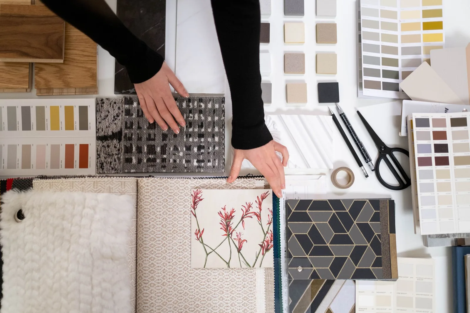 Designer laying out material samples, swatches and drawings on a table while planning a room