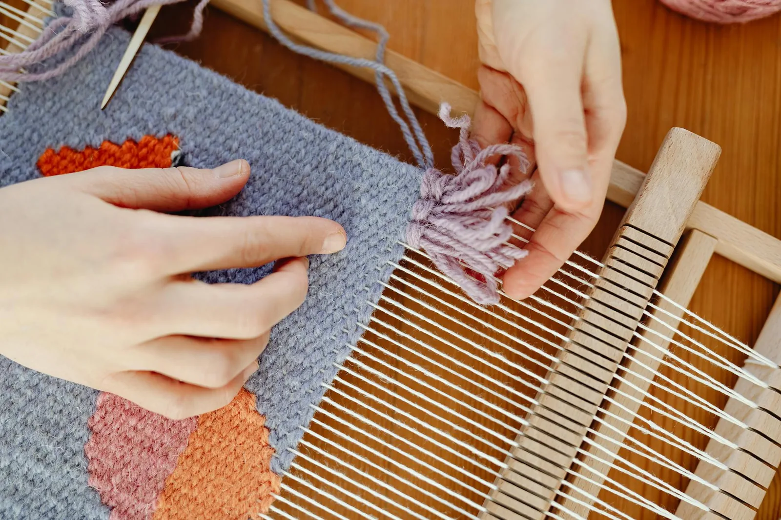 Artisan hands weaving wool on a loom