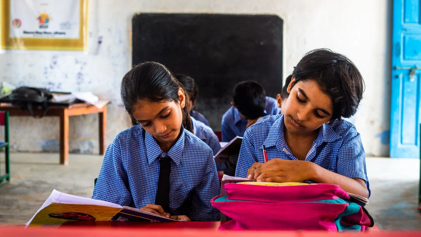 Students in uniform focused on their work at their desks in an Indian classroom